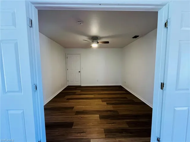 Empty room featuring dark wood-style flooring and a ceiling fan