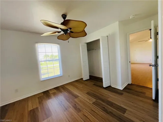 Unfurnished bedroom with ceiling fan, a closet, and dark wood finished floors