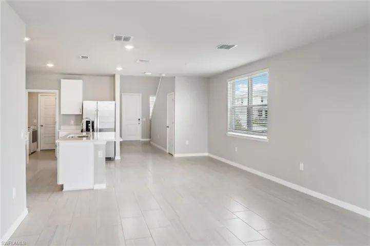 Kitchen with a sink, light countertops, white cabinets, baseboards, and recessed lighting