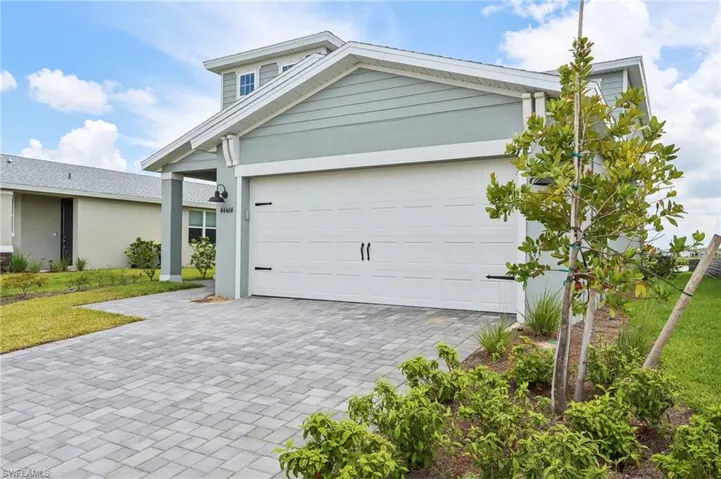 View of front facade featuring decorative driveway, a front yard, an attached garage, and stucco siding
