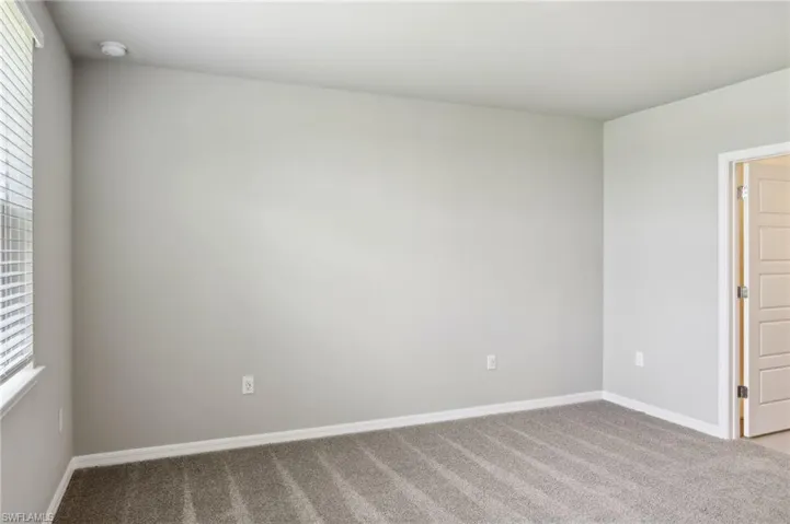 Carpeted spare room featuring a smoke detector and baseboards