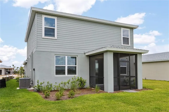 Rear view of property featuring central AC unit, a sunroom, and a yard