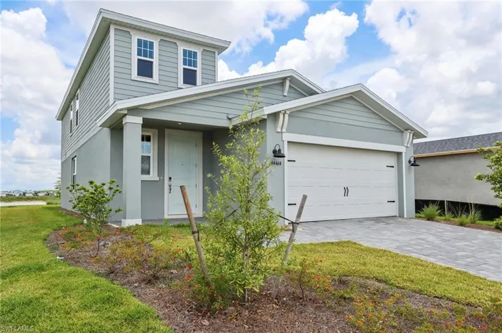 View of front of property featuring a garage, decorative driveway, stucco siding, and a front lawn