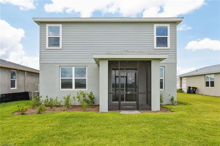 Rear view of property with a lawn, a sunroom, and stucco siding