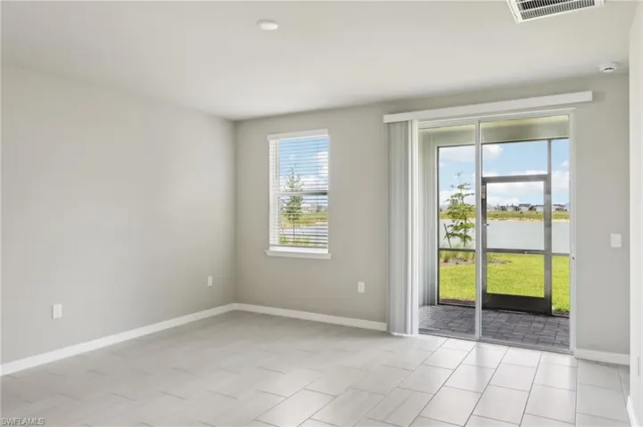 Empty room featuring baseboards, light tile patterned flooring, and a water view