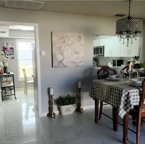 Tiled dining room featuring an inviting chandelier and sink