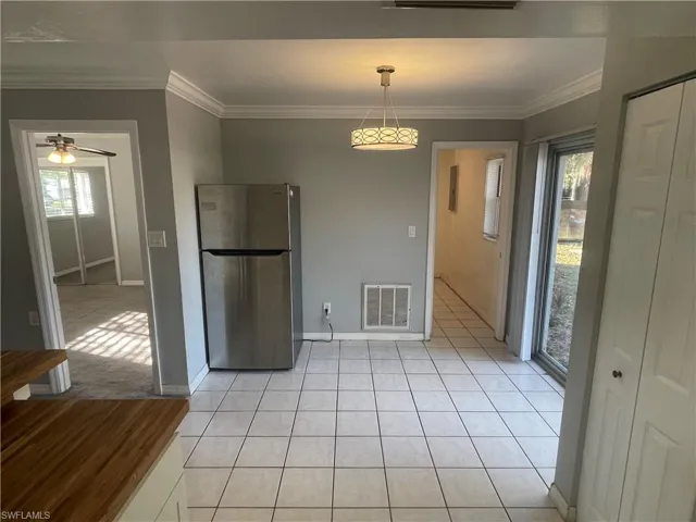 Kitchen featuring ornamental molding, freestanding refrigerator, light tile patterned floors, a ceiling fan, and hanging light fixtures