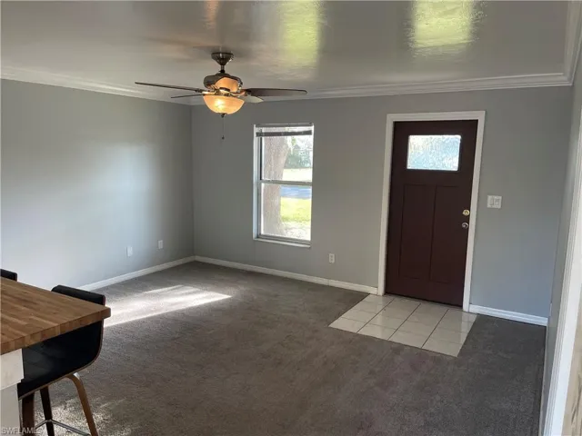 Foyer entrance featuring light colored carpet, ornamental molding, and ceiling fan