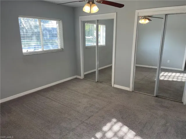 Unfurnished bedroom with multiple closets, carpet floors, and a ceiling fan