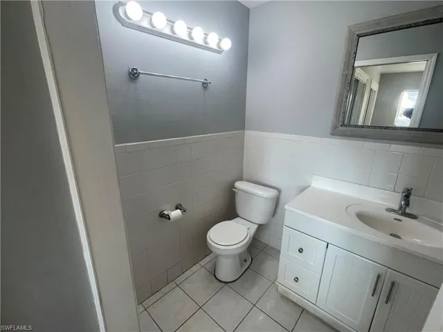 Bathroom with vanity, tile walls, light tile patterned flooring, and a wainscoted wall