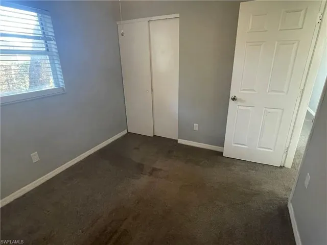 Unfurnished bedroom featuring dark carpet and a closet