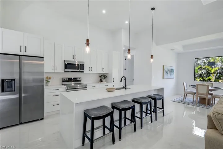 Kitchen featuring stainless steel appliances, a kitchen island with sink, a sink, white cabinets, and recessed lighting