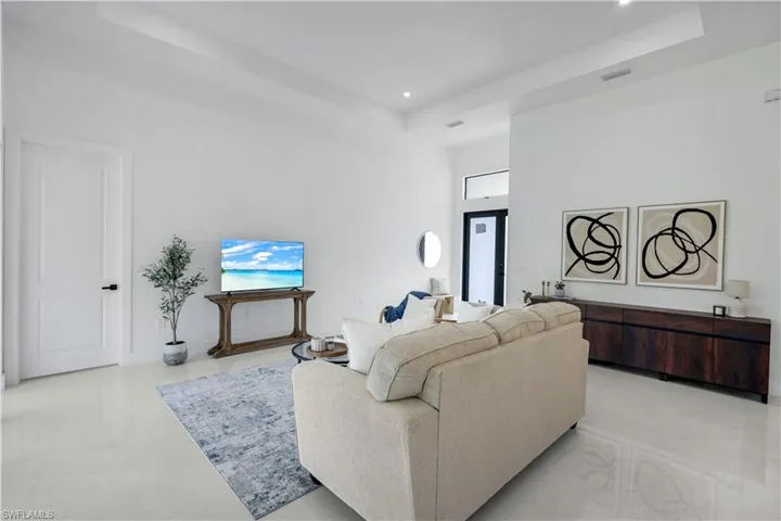 Living room with a tray ceiling, recessed lighting, and a towering ceiling