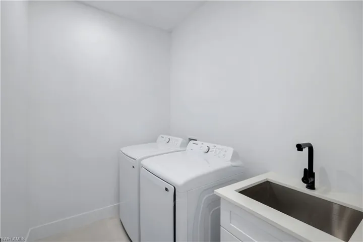 Clothes washing area featuring independent washer and dryer, cabinet space, and baseboards