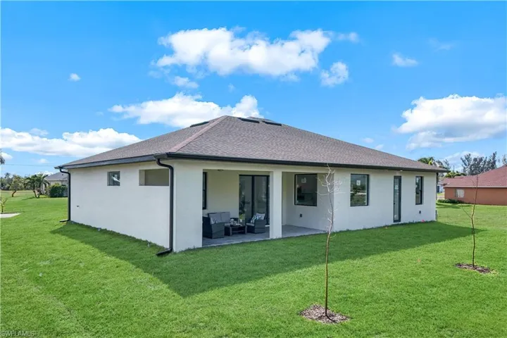 Rear view of house featuring outdoor lounge area, a lawn, a patio, and stucco siding