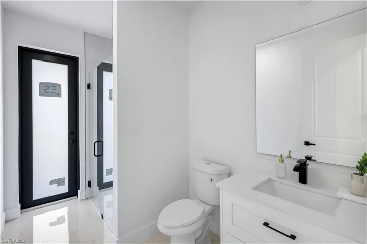 Full bathroom with toilet, a shower stall, vanity, and baseboards