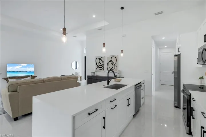 Kitchen featuring appliances with stainless steel finishes, a sink, recessed lighting, white cabinetry, and open floor plan