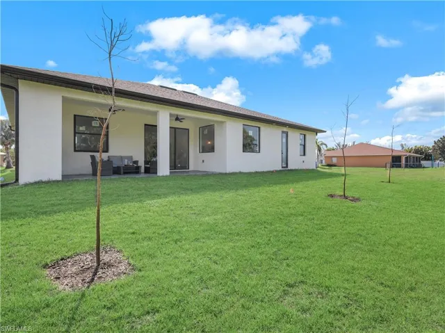 Rear view of property with stucco siding, an outdoor hangout area, ceiling fan, a yard, and a patio