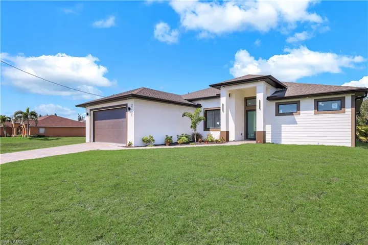 Prairie-style home featuring driveway, a front yard, an attached garage, and a shingled roof