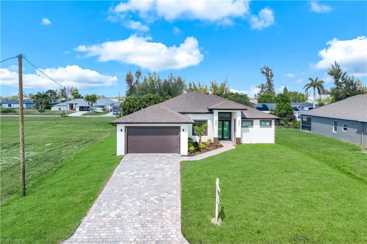 View of front of property featuring a garage, a front lawn, decorative driveway, and a residential view
