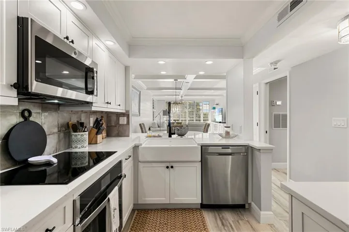 Kitchen featuring kitchen peninsula, appliances with stainless steel finishes, light hardwood / wood-style floors, and white cabinetry