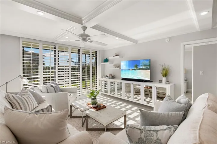 Living room with beamed ceiling, ceiling fan, ornamental molding, and coffered ceiling