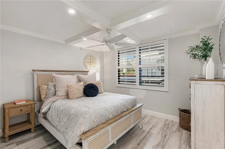 Bedroom with hardwood / wood-style flooring, ceiling fan, and ornamental molding