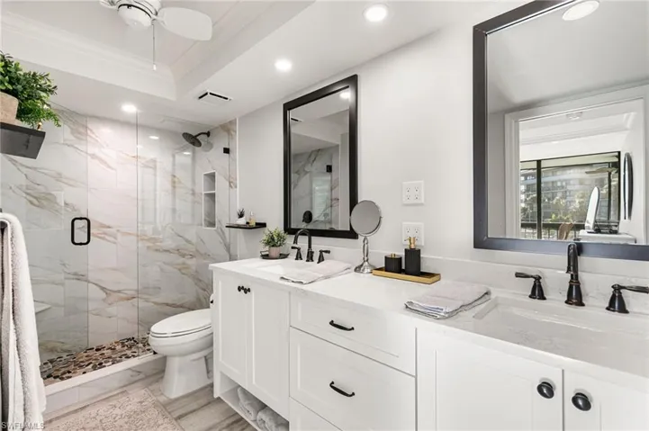 Bathroom featuring ceiling fan, walk in shower, toilet, vanity, and ornamental molding