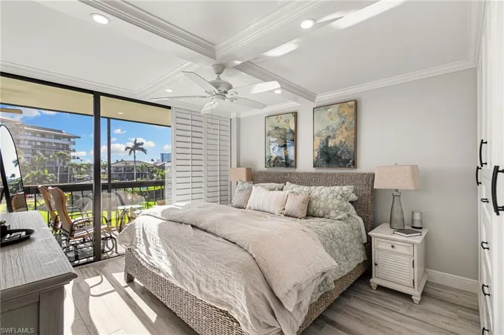 Bedroom featuring ceiling fan, access to exterior, light wood-type flooring, ornamental molding, and beamed ceiling