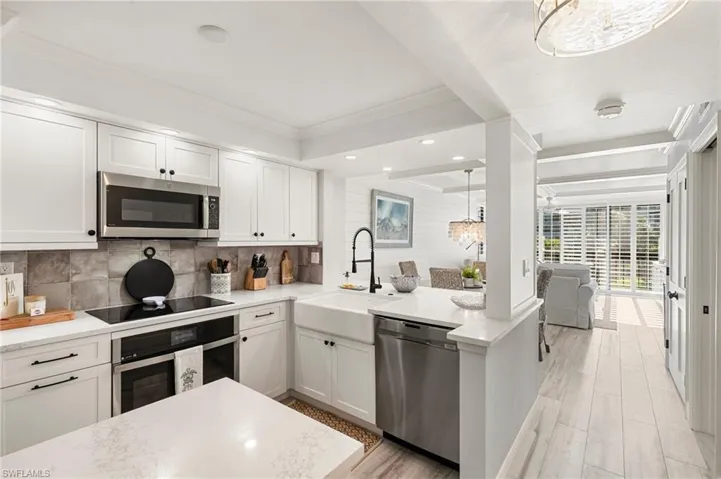 Kitchen featuring appliances with stainless steel finishes, crown molding, sink, white cabinets, and hanging light fixtures