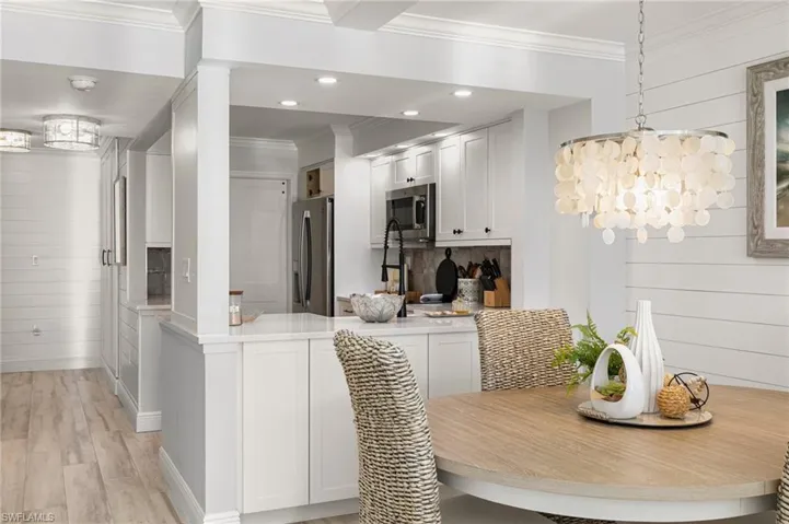 Dining room with light hardwood / wood-style floors, crown molding, and wood walls