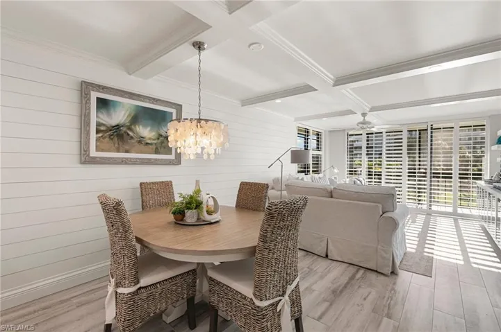 Dining room with beamed ceiling, light wood-type flooring, wooden walls, and coffered ceiling
