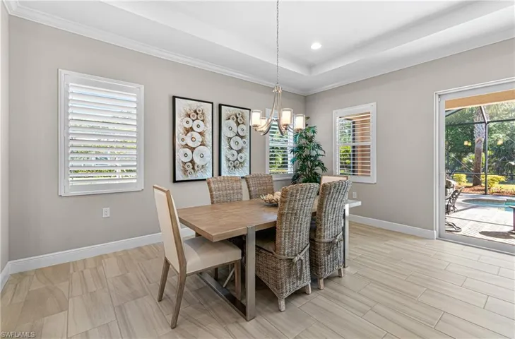 DINING ROOM WITH A MODERN TABLE & CHAIRS PLUS PLANTATION SHUTTERS, CROWN MOLDING & ALL WITH A VIEW OF YOUR BEAUTIFUL POOL.