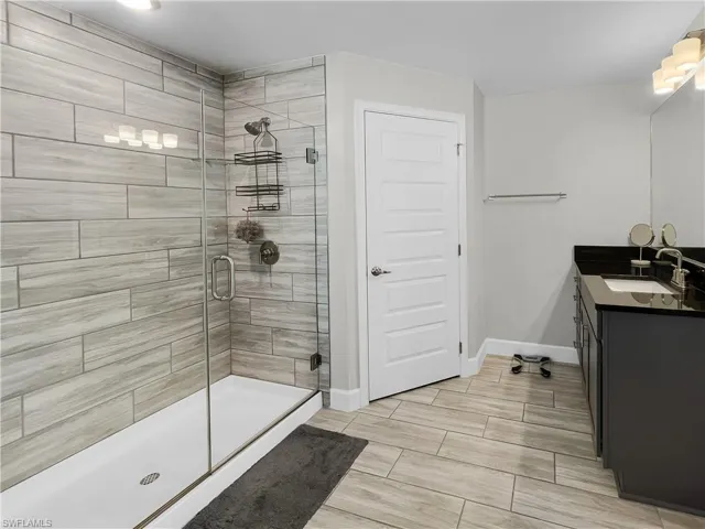 Bathroom with vanity, a stall shower, and wood finish floors