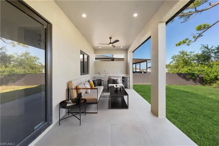 Fenced backyard with an outdoor hangout area, ceiling fan, and a patio area