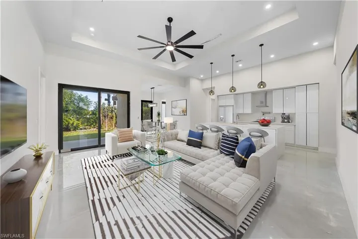 Living room featuring a raised ceiling, a towering ceiling, a ceiling fan, and recessed lighting