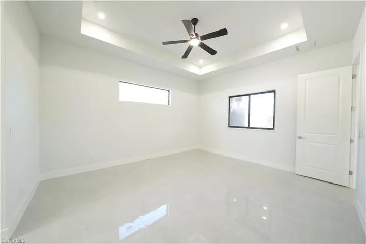 Unfurnished room featuring a raised ceiling, a ceiling fan, and recessed lighting