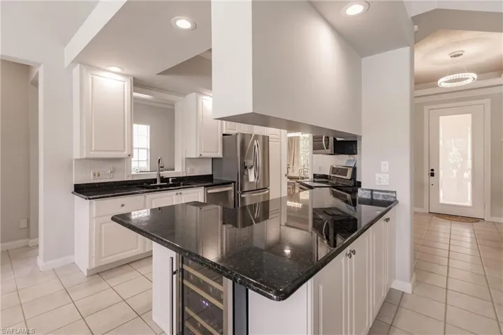 Kitchen featuring dark stone counters, appliances with stainless steel finishes, sink, and light tile patterned floors