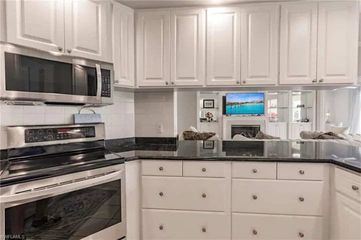 Kitchen with white cabinets, appliances with stainless steel finishes, and decorative backsplash