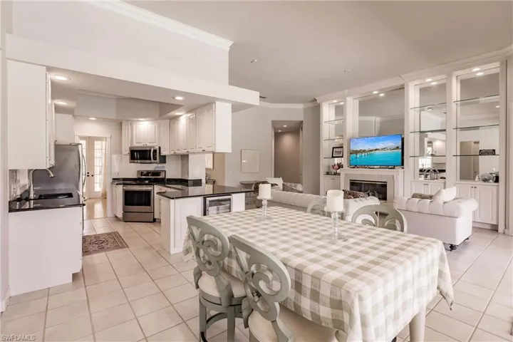 Tiled dining space with crown molding, wine cooler, and sink