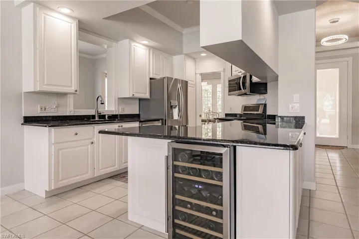Kitchen featuring white cabinetry, beverage cooler, sink, appliances with stainless steel finishes, and light tile patterned flooring