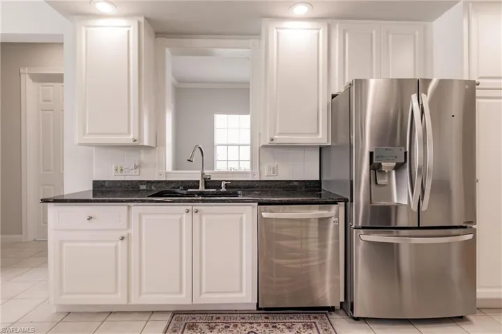 Kitchen with white cabinetry, tasteful backsplash, sink, appliances with stainless steel finishes, and light tile patterned flooring