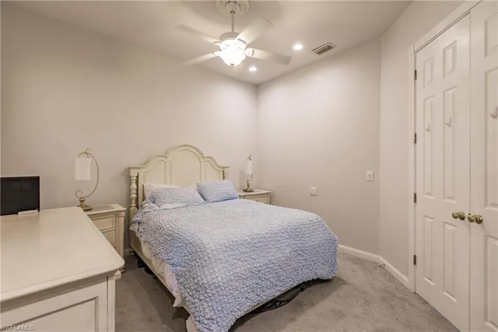 Carpeted bedroom with ceiling fan and a closet