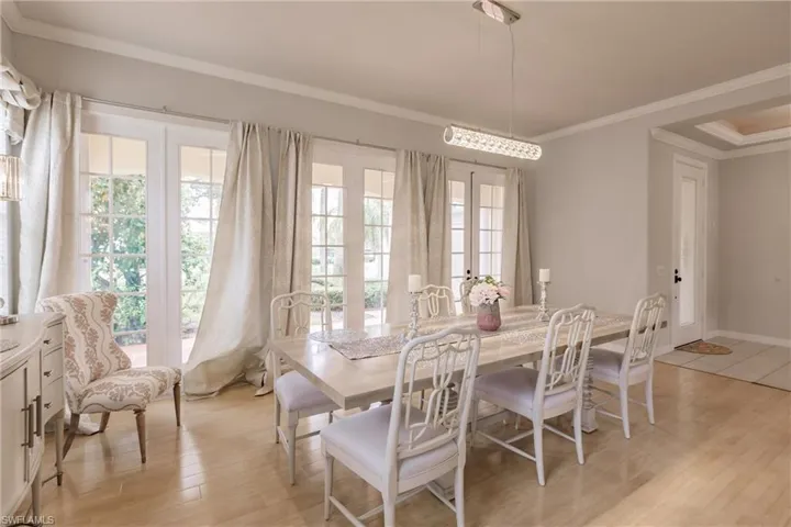 Dining area with crown molding, light hardwood / wood-style flooring, and french doors