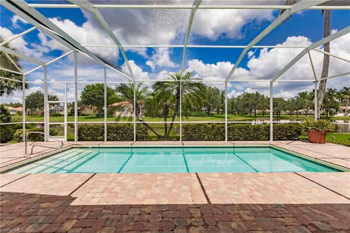 View of pool with glass enclosure and a patio