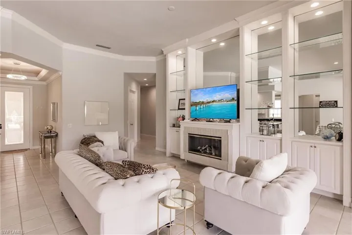 Living room with crown molding, light tile patterned floors, and a tile fireplace