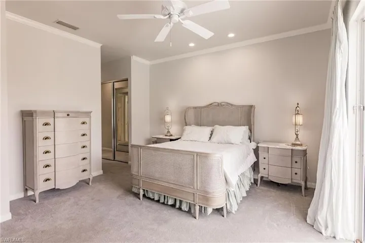 Bedroom featuring a closet, light colored carpet, crown molding, and ceiling fan