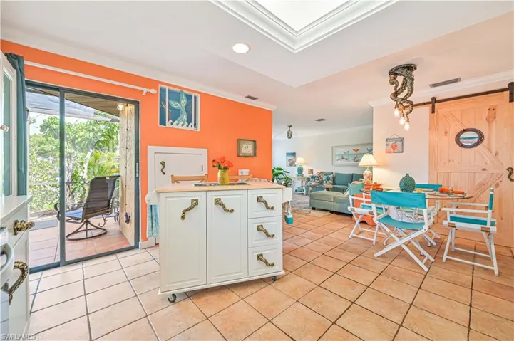 Kitchen with light tile patterned floors, a barn door, white cabinets, ornamental molding, and a center island