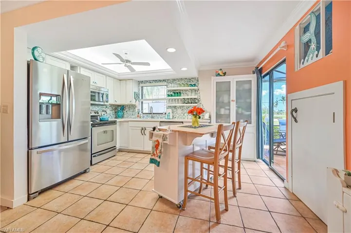 Kitchen with light countertops, backsplash, appliances with stainless steel finishes, white cabinets, and light tile patterned flooring