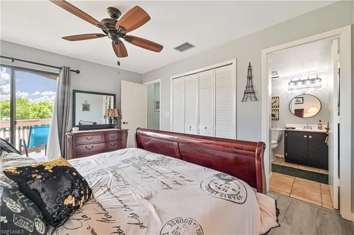 Bedroom featuring a closet, visible vents, ensuite bath, wood finished floors, and access to outside